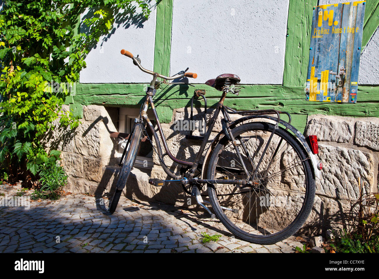 Vieux vélo rouillé dans une rue pavée de maisons médiévales à pans de bois dans le patrimoine mondial de l'Unesco ville de Quedlinburg, Allemagne. Banque D'Images