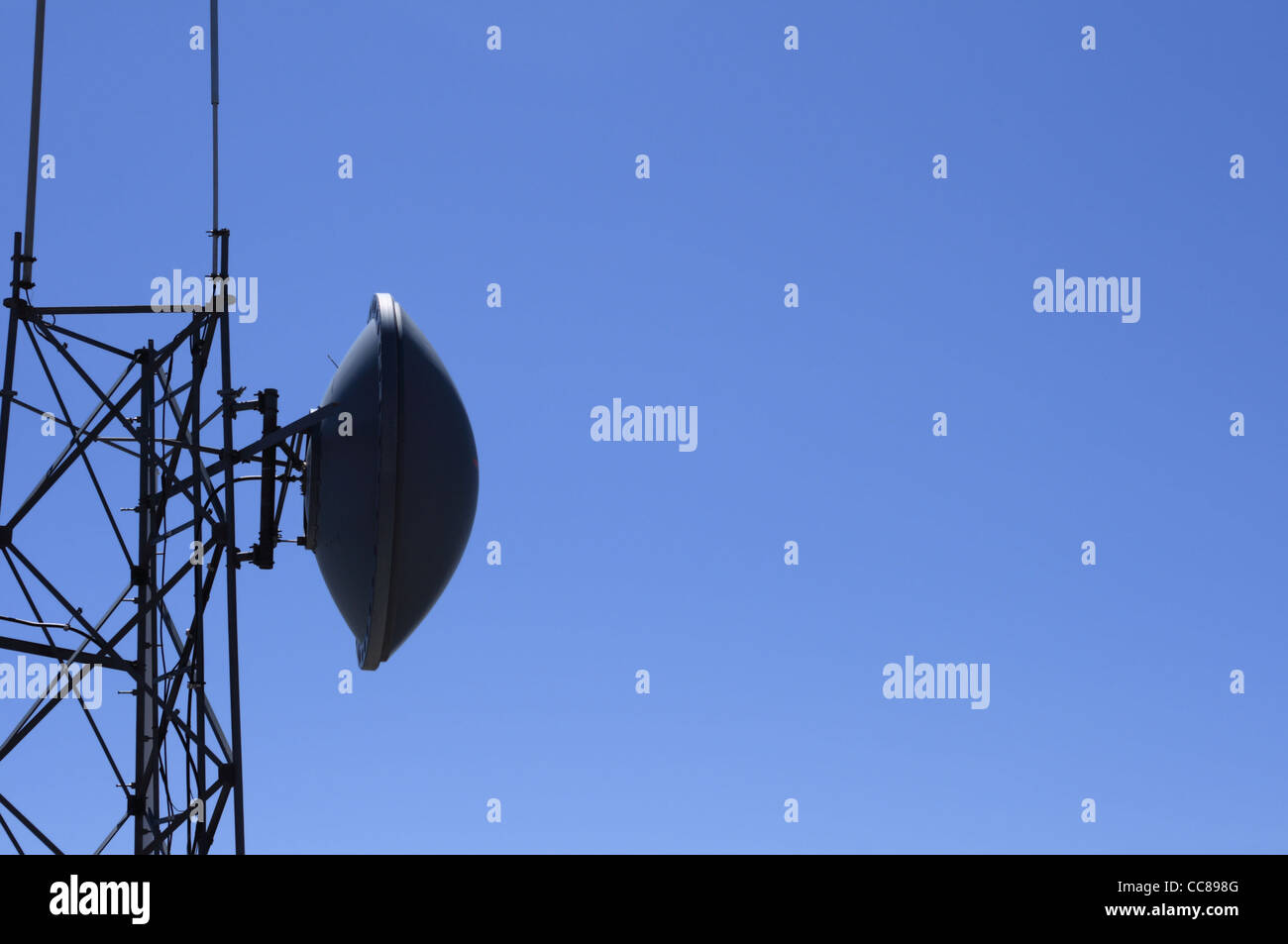 Tour de l'antenne micro-ondes sombre ciel bleu avec copie espace sur le côté Banque D'Images