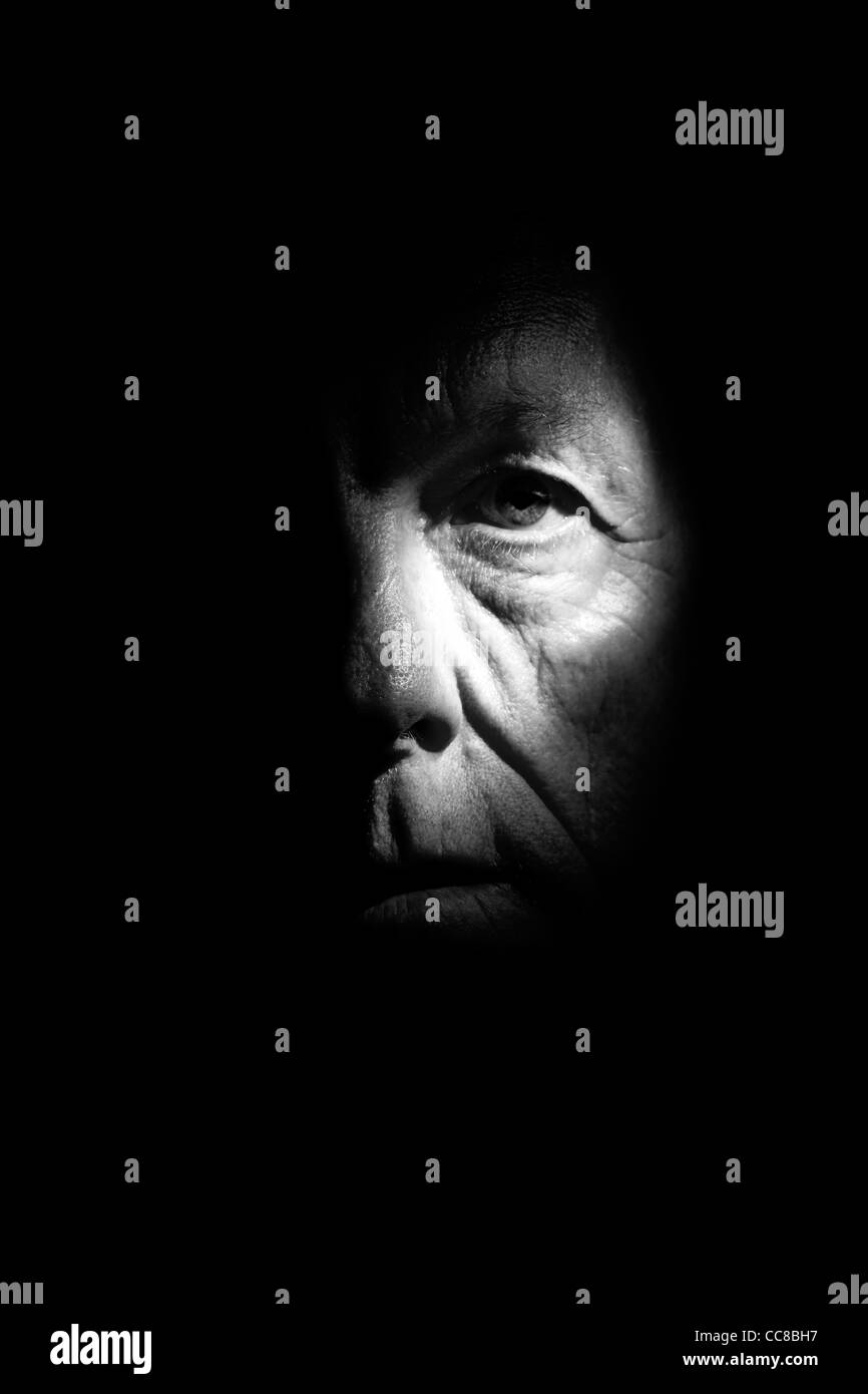 Man looking at camera sur fond noir avec des stries de lumière à travers son oeil tous en noir et blanc. Banque D'Images