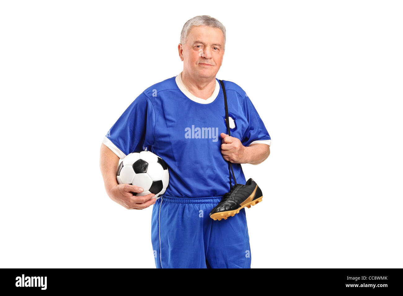 Un cadre portant un sport wear tenant un chaussures de football et de football Banque D'Images