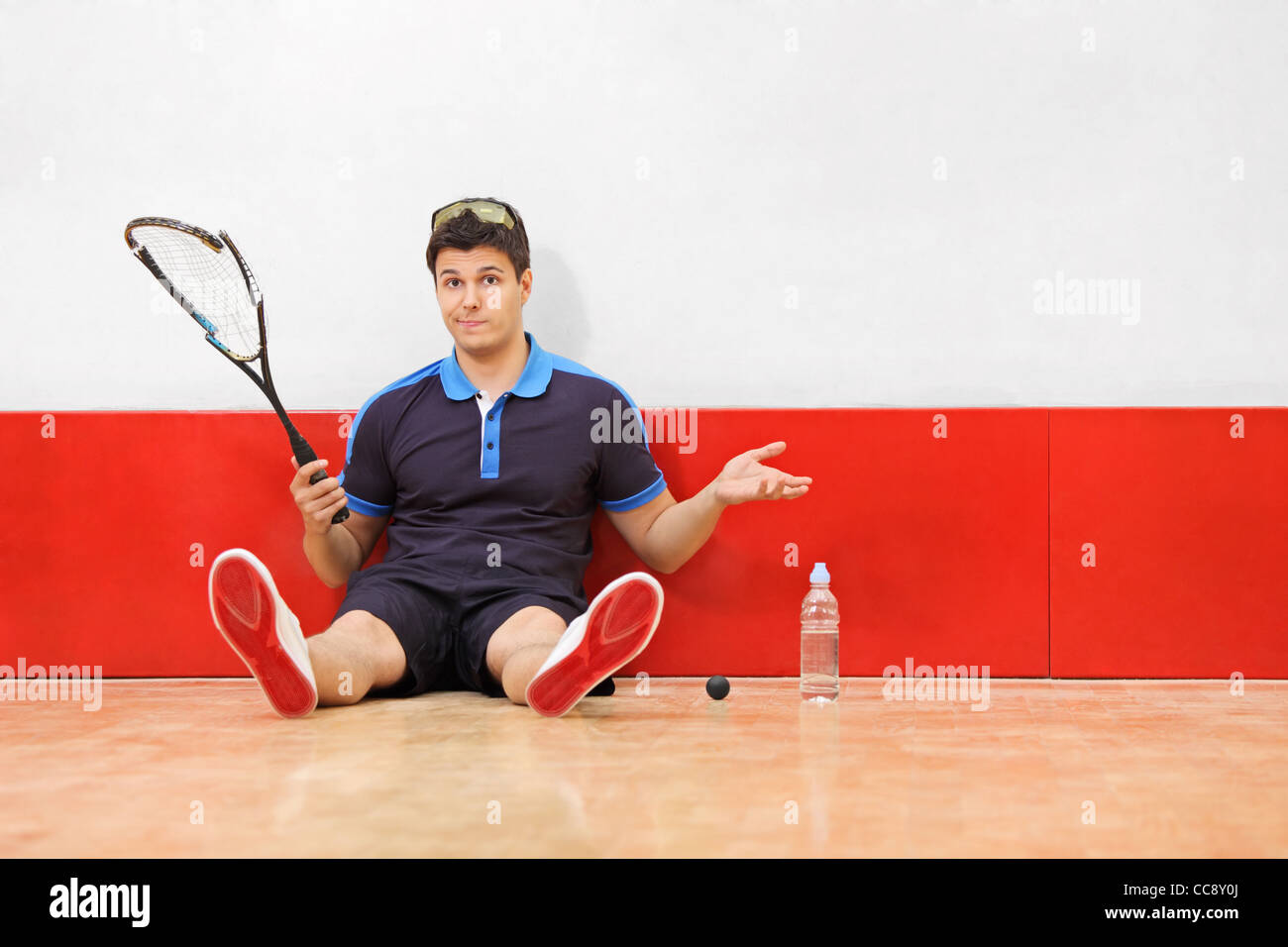 Un jeune joueur de squash déçu tenant une raquette cassée Banque D'Images