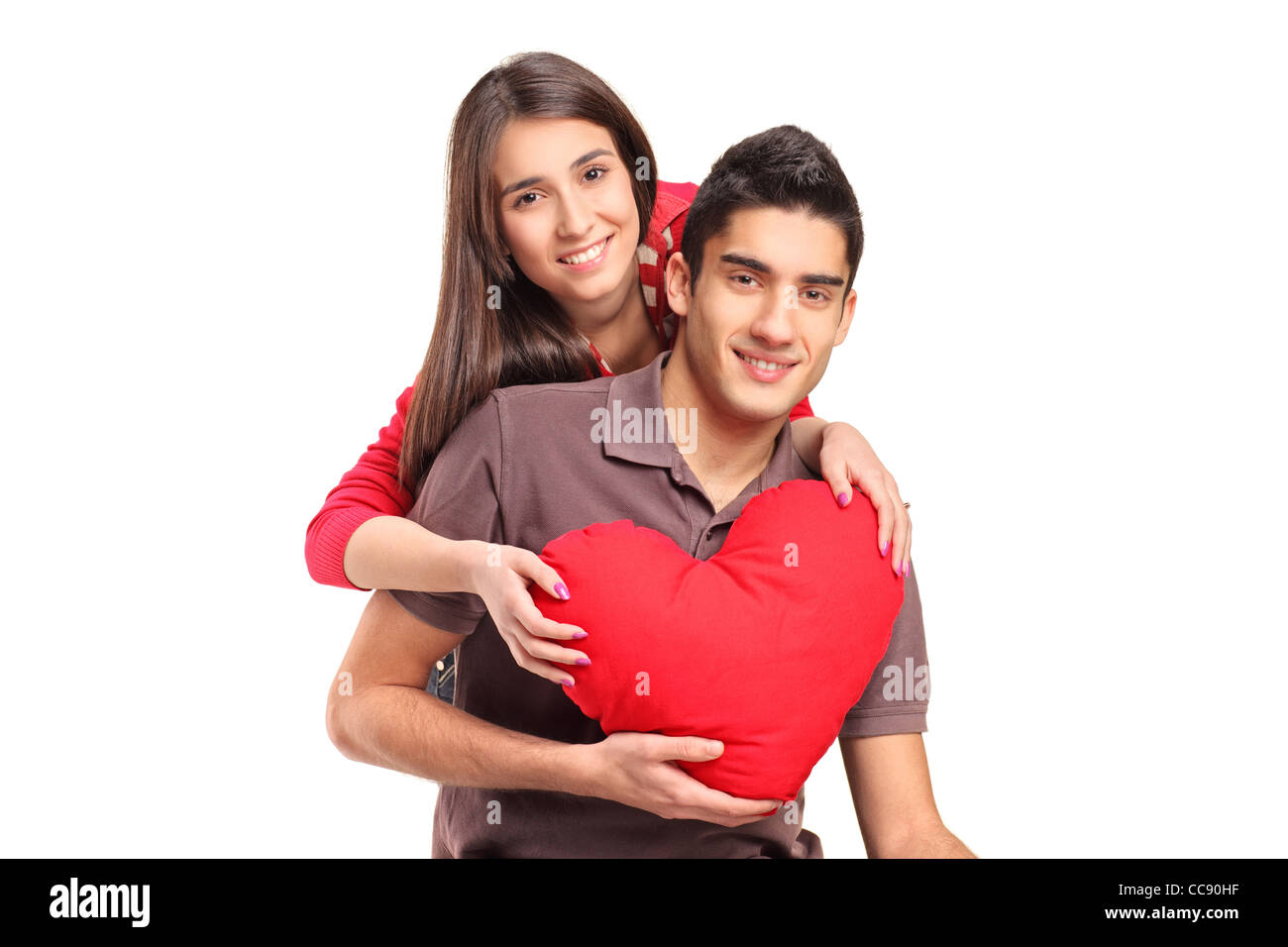 Jeune couple d'amoureux dans une étreinte tenant un oreiller en forme de  coeur rouge Photo Stock - Alamy