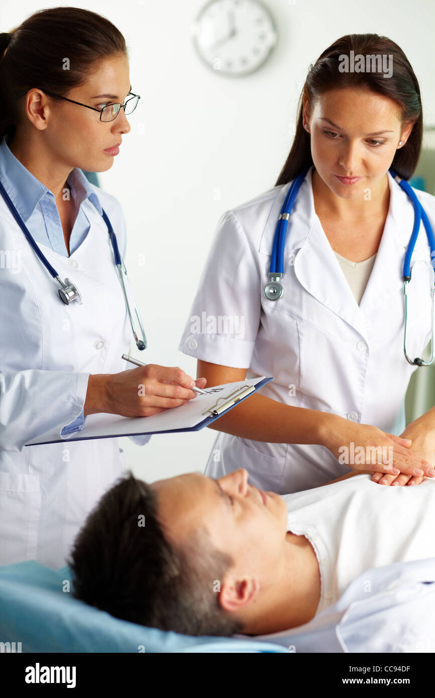 Portrait of female doctors pendant le traitement médical du patient in hospital Banque D'Images