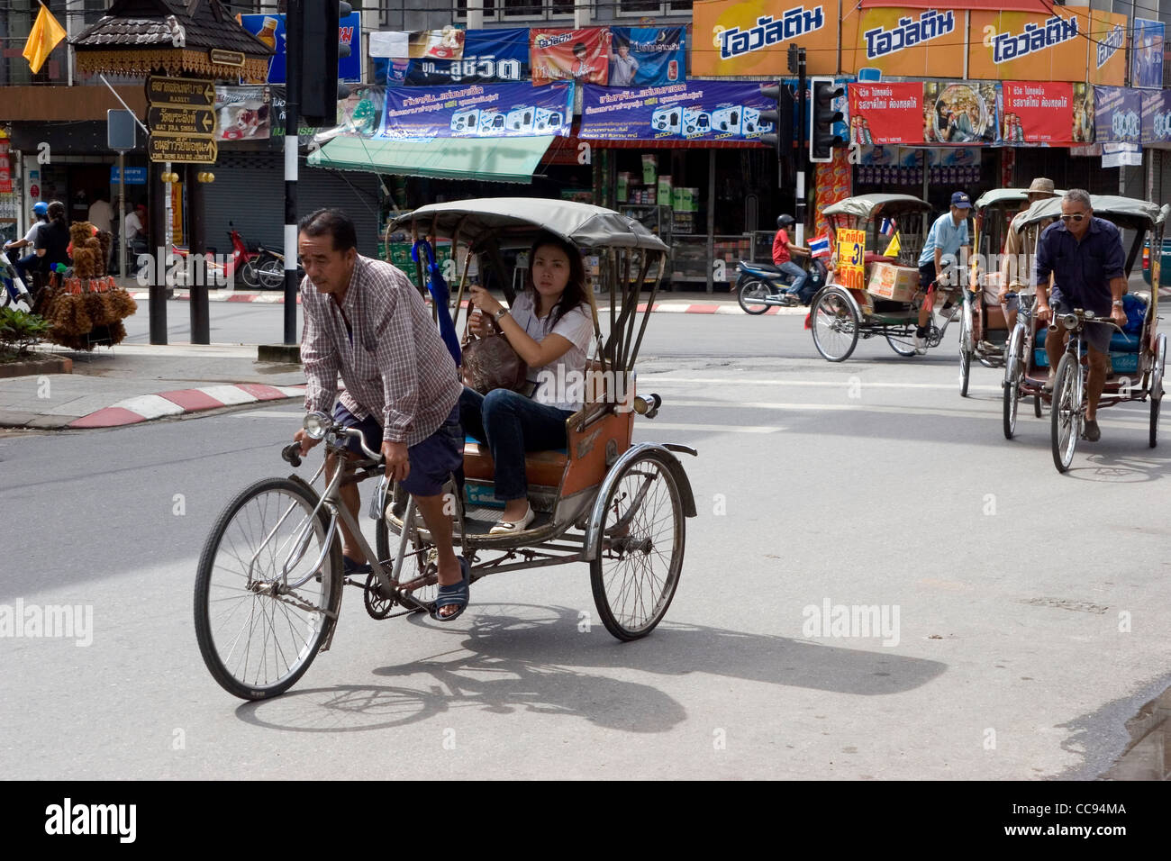 Un groupe de pilotes sont cyclo touristes donnant un tour sur une rue de ville de Chiang Rai, Thaïlande. Banque D'Images