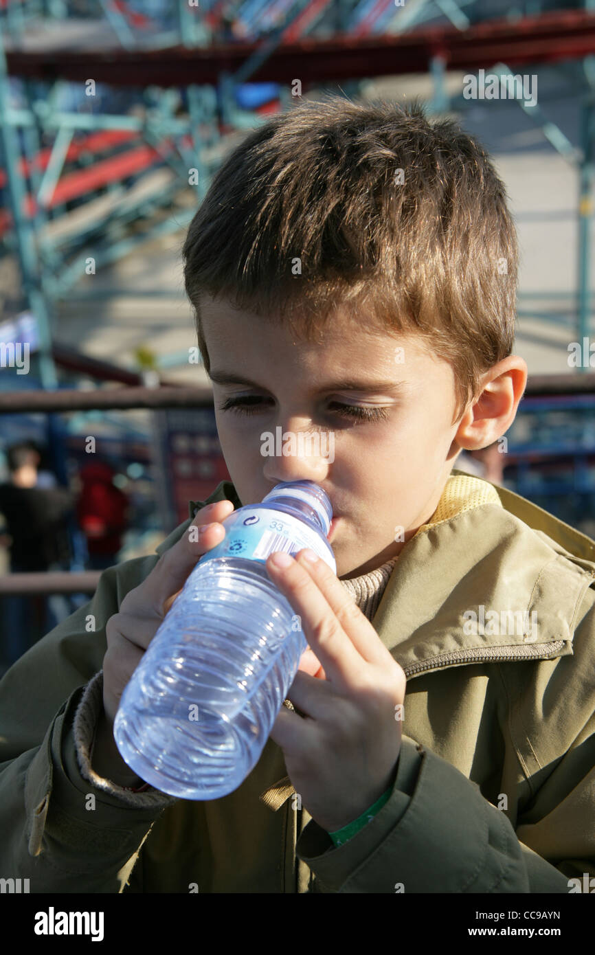Un garçon de six ans, l'eau potable à partir d'une bouteille. Banque D'Images