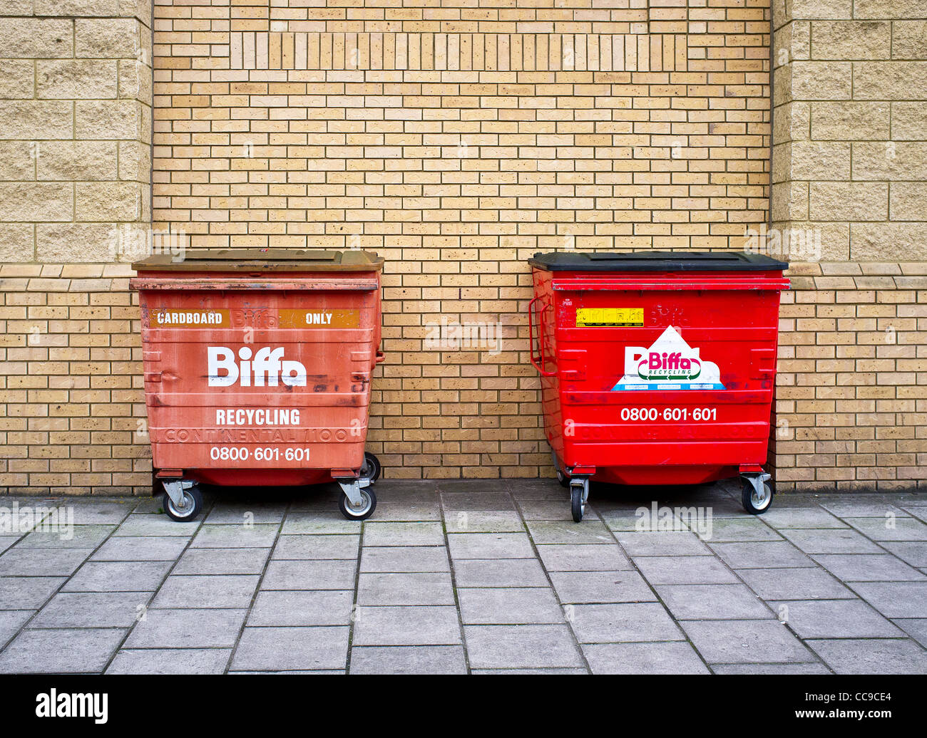 Deux bacs de recyclage contre un mur de briques Banque D'Images