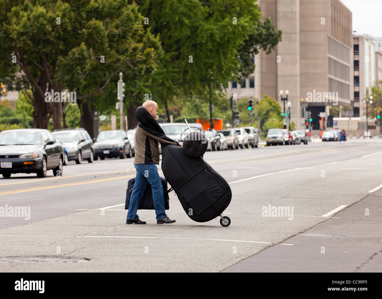 Un homme portant une basse classique de l'autre côté de la rue - USA Banque D'Images