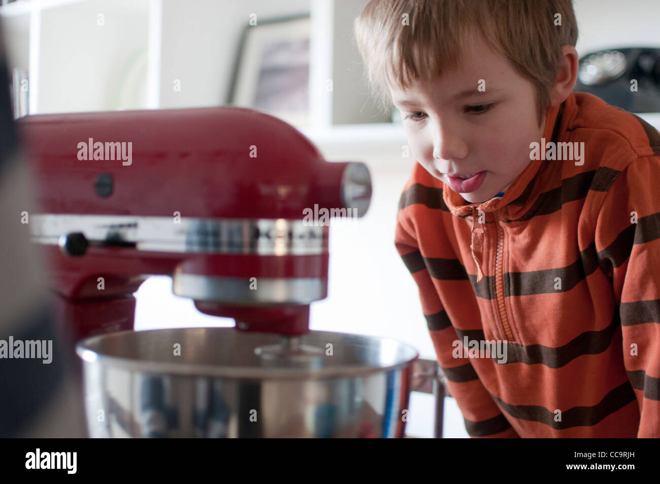 Jeune garçon dans la cuisine faire un gâteau au chocolat avec un mélangeur de kitchenaid. Banque D'Images