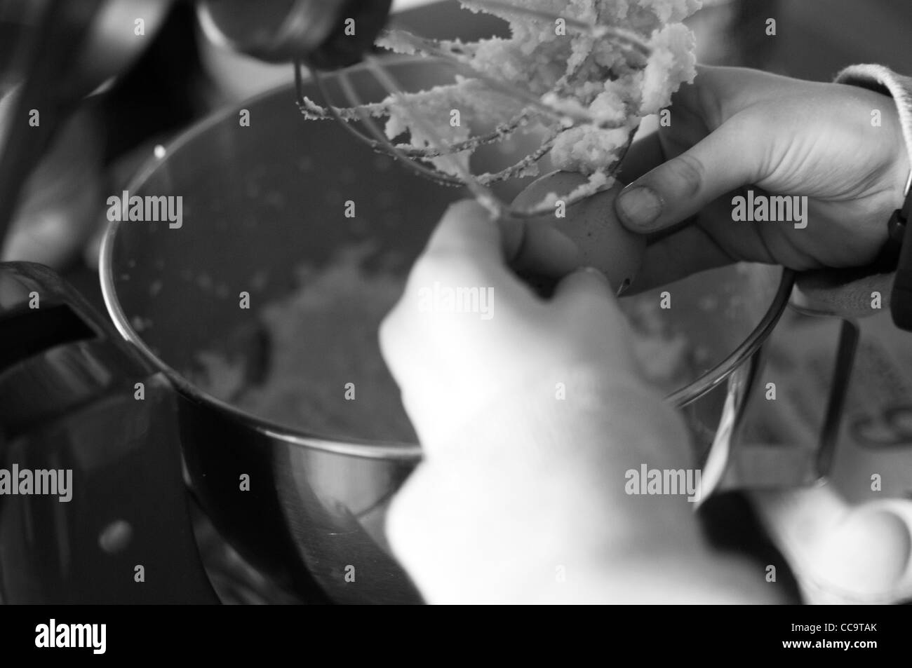 Close up de fissuration les mains de l'enfant un oeuf dans un bol de mélange à gâteau Banque D'Images
