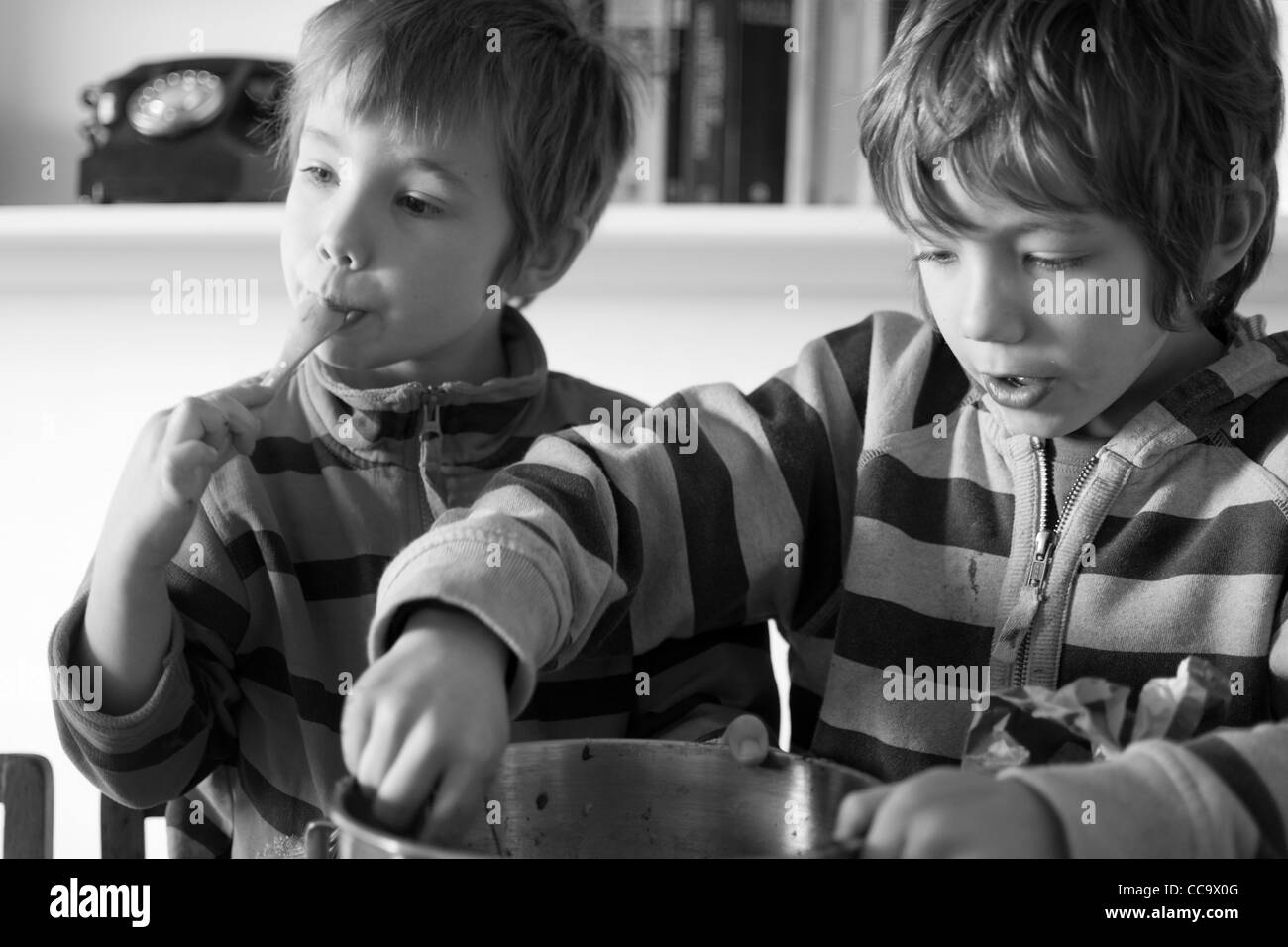 Deux jeunes garçons la confection d'un gâteau au chocolat - lécher le mélange à gâteau hors du bol Banque D'Images