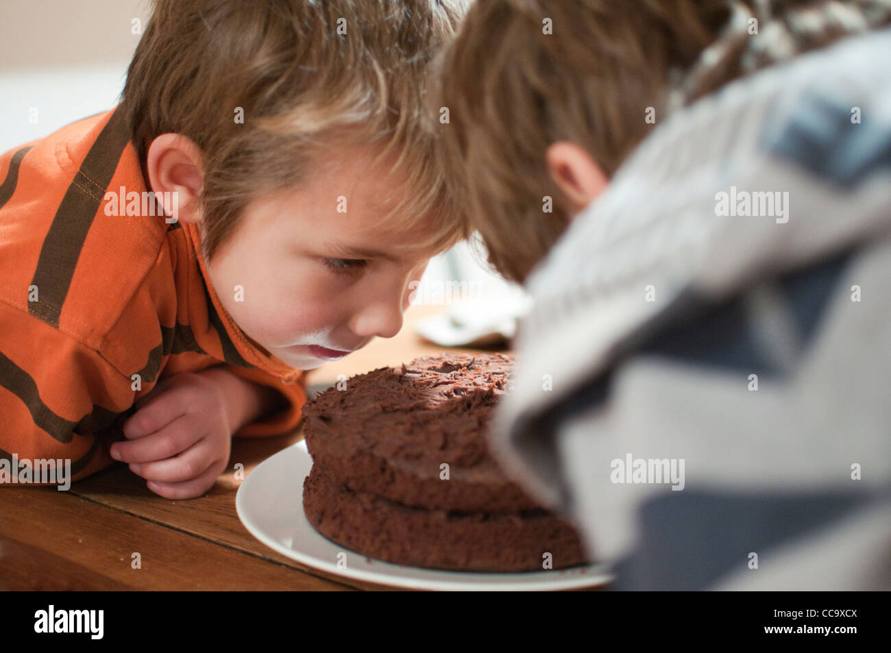 Les jeunes professionnels garçon assis à la table en train de manger un morceau de gâteau au chocolat Banque D'Images