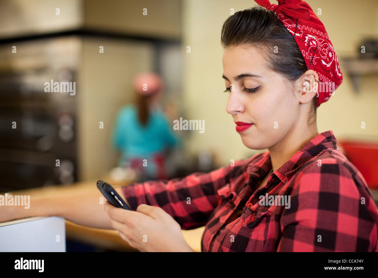 Young woman using cellphone in bakery Banque D'Images