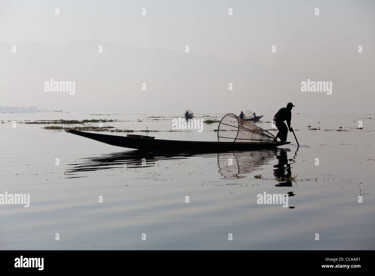 Haunting pêcheur tribal sur le lac Inle en Birmanie. Technique unique de jambe d'aviron et conique résille. Banque D'Images