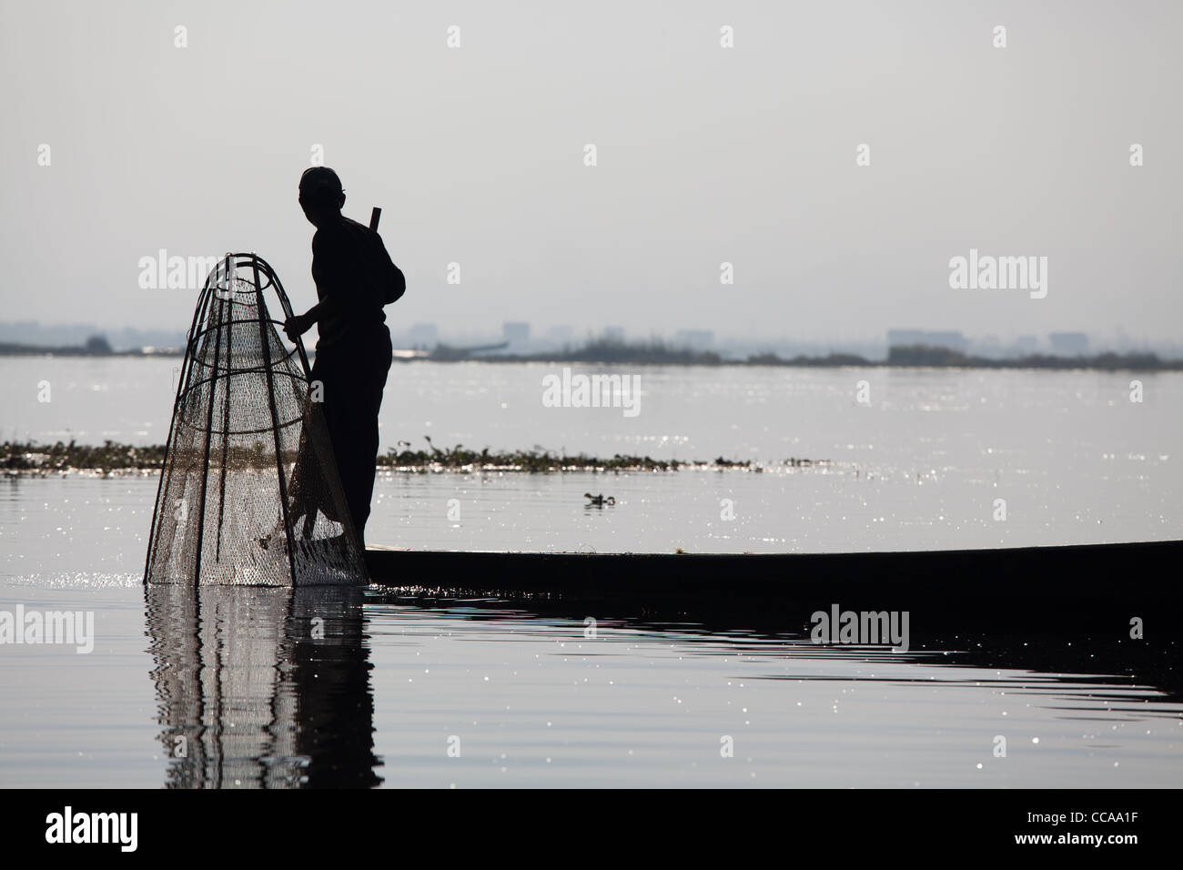 Haunting pêcheur tribal sur le lac Inle en Birmanie. Technique unique de jambe d'aviron et conique résille. Banque D'Images