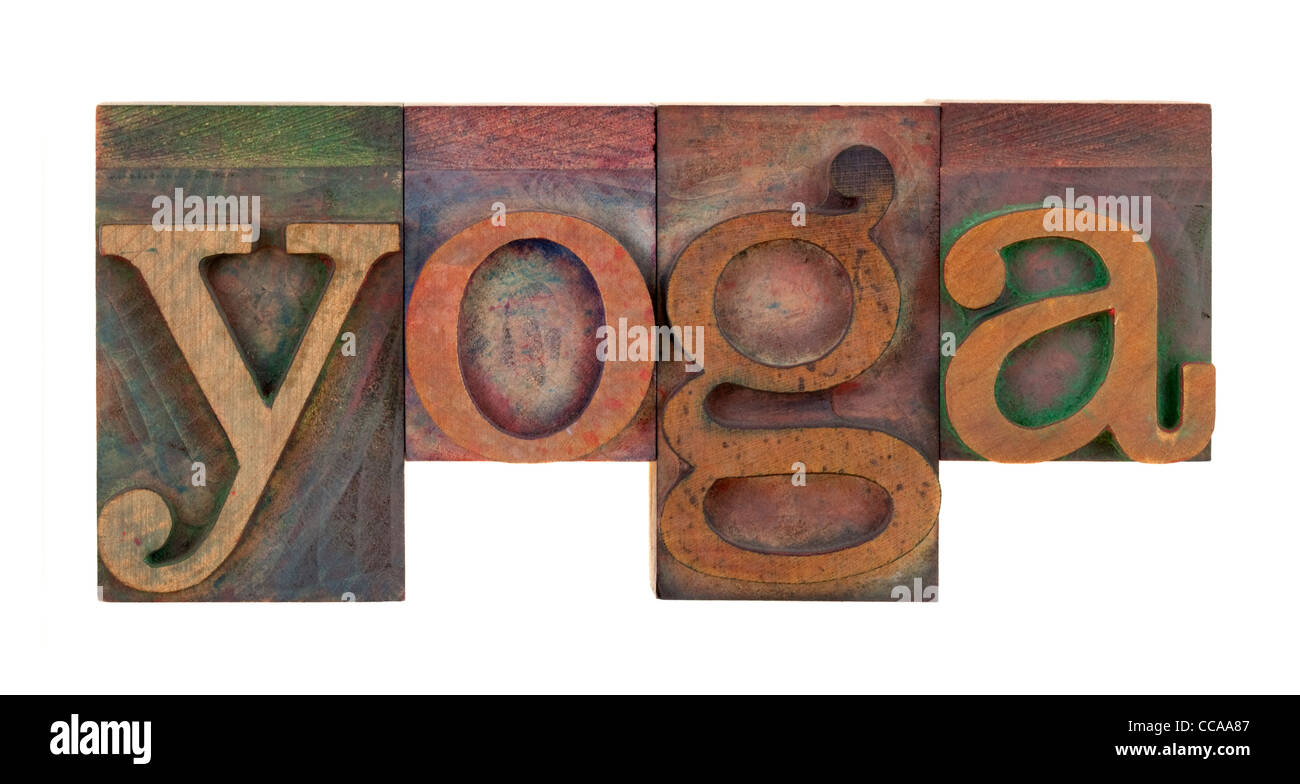 Le mot yoga en bois vintage type letterpress blocs, tachés par l'encre de couleur, isolated on white Banque D'Images