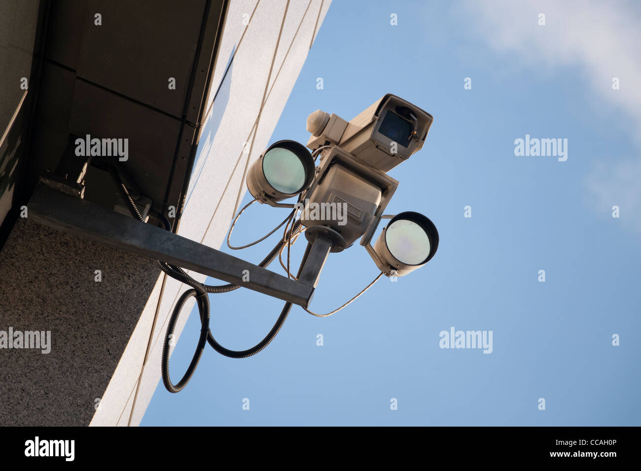 Une caméra de surveillance reliée à un bâtiment sur un ciel clair et lumineux 24. Banque D'Images
