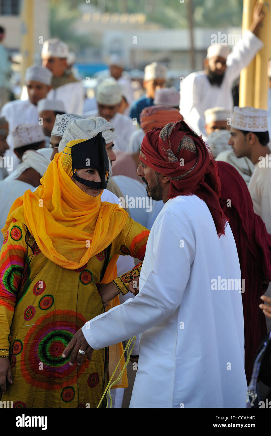 Une femme musulmane avec le visage-masque Bedu parle librement au marché de la chèvre du dimanche à Nizwa ; Al Dakhiliyah, Oman. Banque D'Images