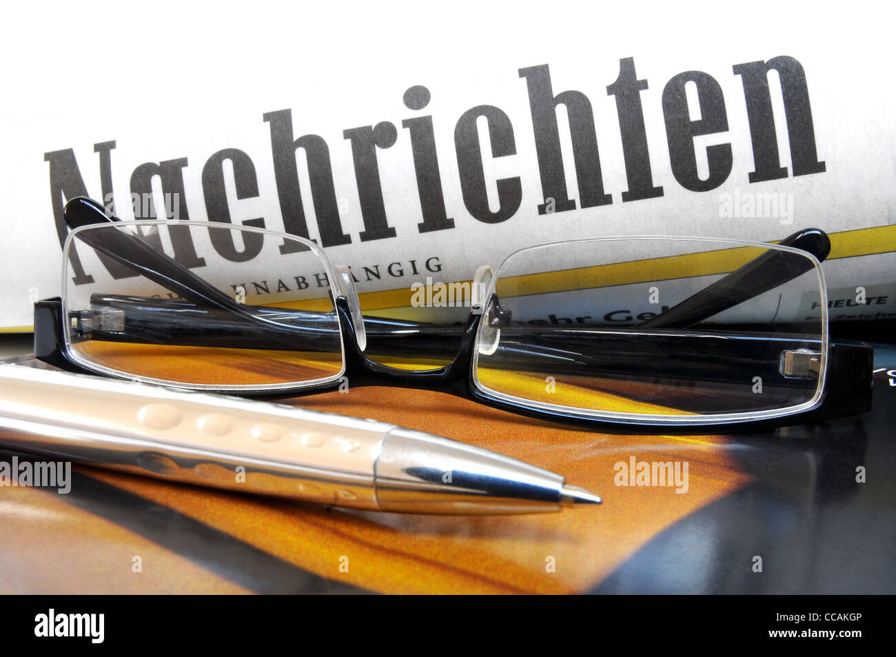 Verres et stylo à bille sur le dessus d'un couvercle multicolore avec lettrage 'News' en langue allemande Banque D'Images