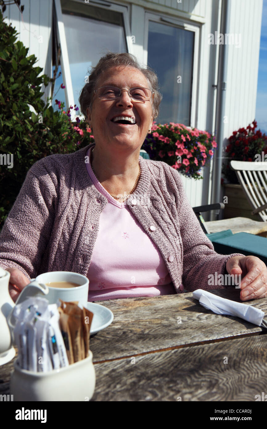 Pensionné britannique de rire tout en vous relaxant avec une tasse de thé Banque D'Images
