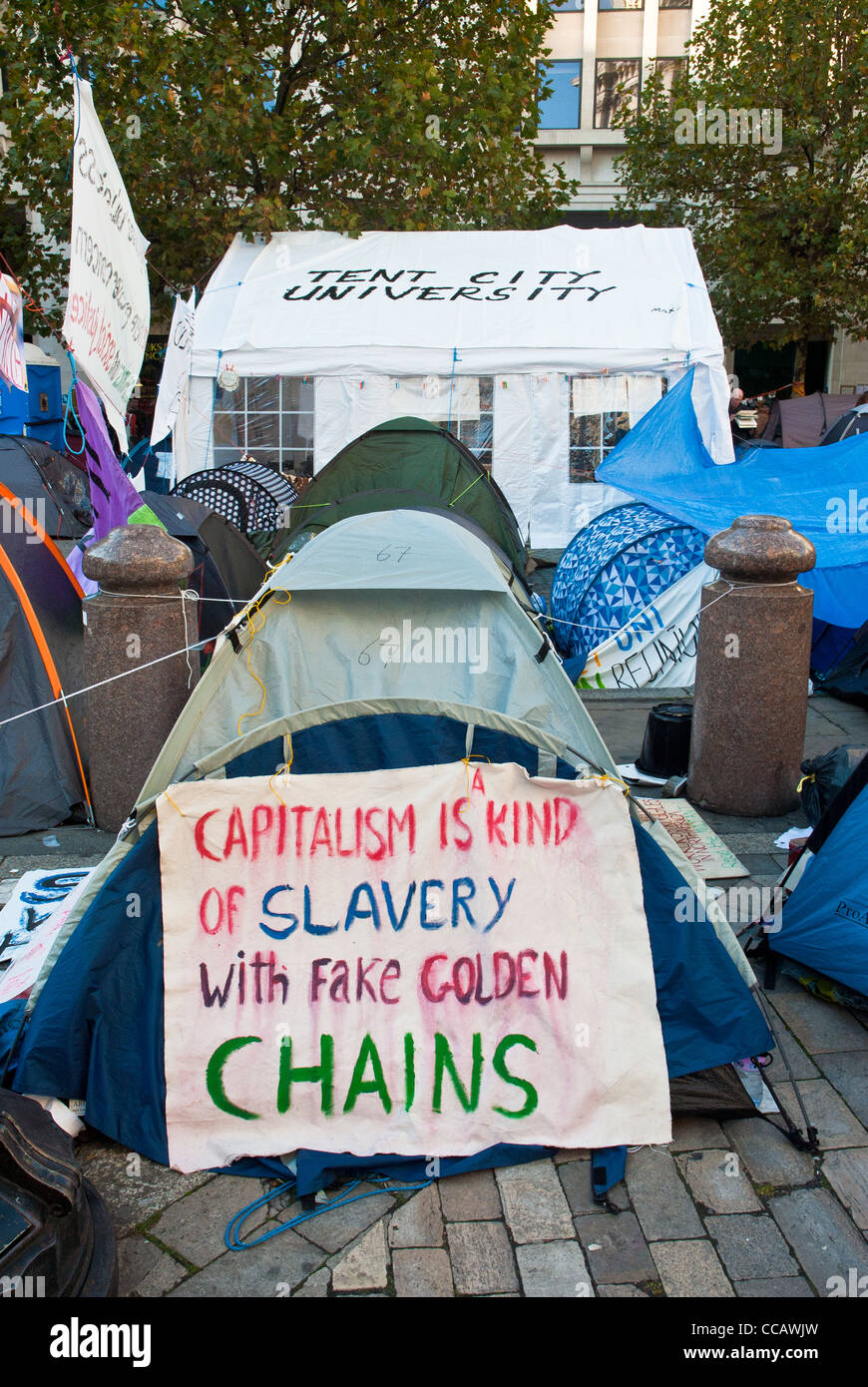 Occupy London St Paul, devise "le capitalisme est une sorte d'esclavage avec de faux des chaînes d'or' et 'Ville tente derrière l'Université'. Banque D'Images