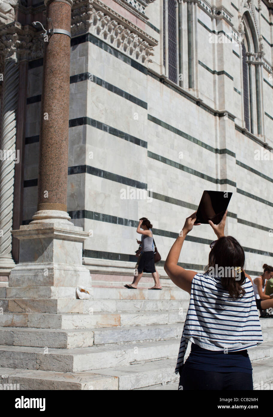 Une femme à l'aide de son Apple ipad pour prendre des photos sur l'extérieur de la Cathédrale, Sienne. L'Italie. Banque D'Images