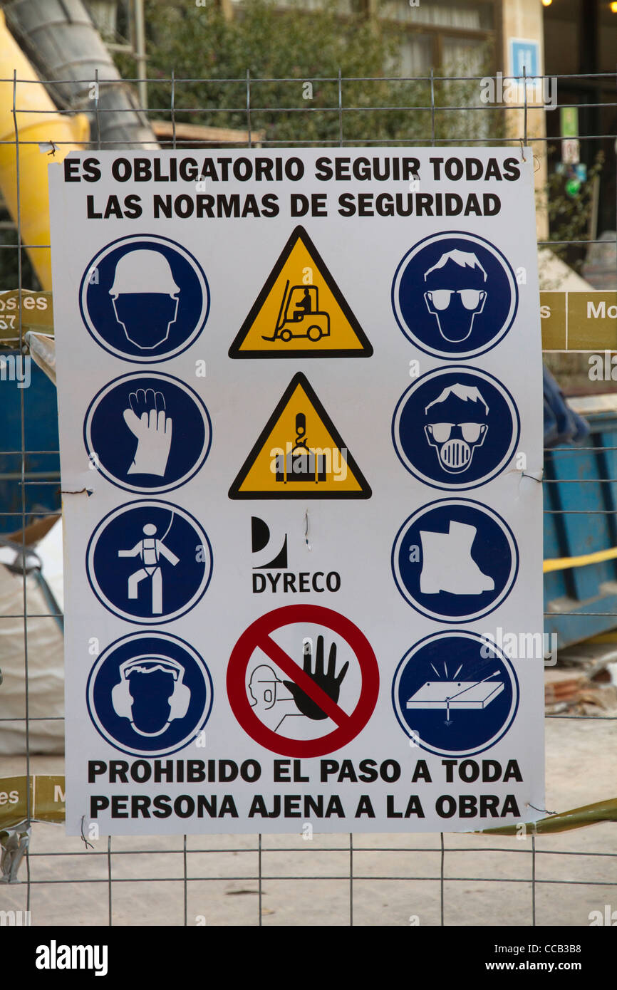 Les signes de sécurité Avertissement hispanic sur la clôture d'un chantier de l'Espagne Banque D'Images