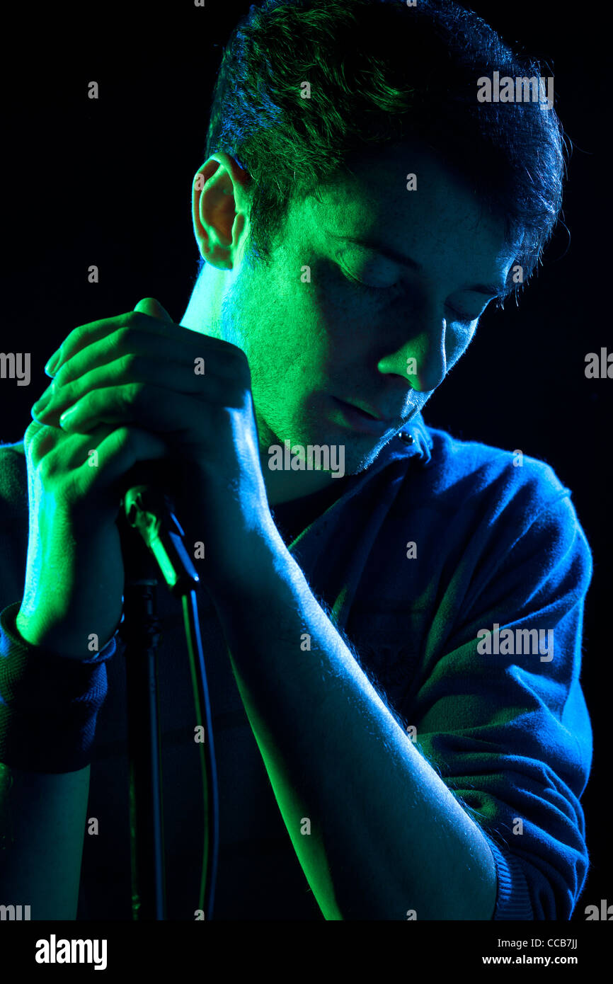 Chanteur Holding Microphone sur fond noir Banque D'Images