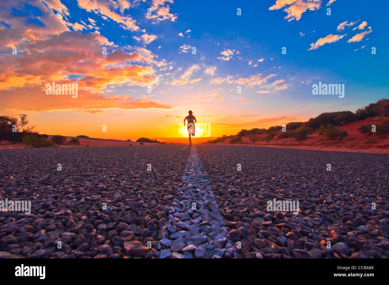 Coureuse du jogging au lever du soleil sur une route dans l'Outback australien, Monkey Mia, Australie occidentale, Australie Banque D'Images