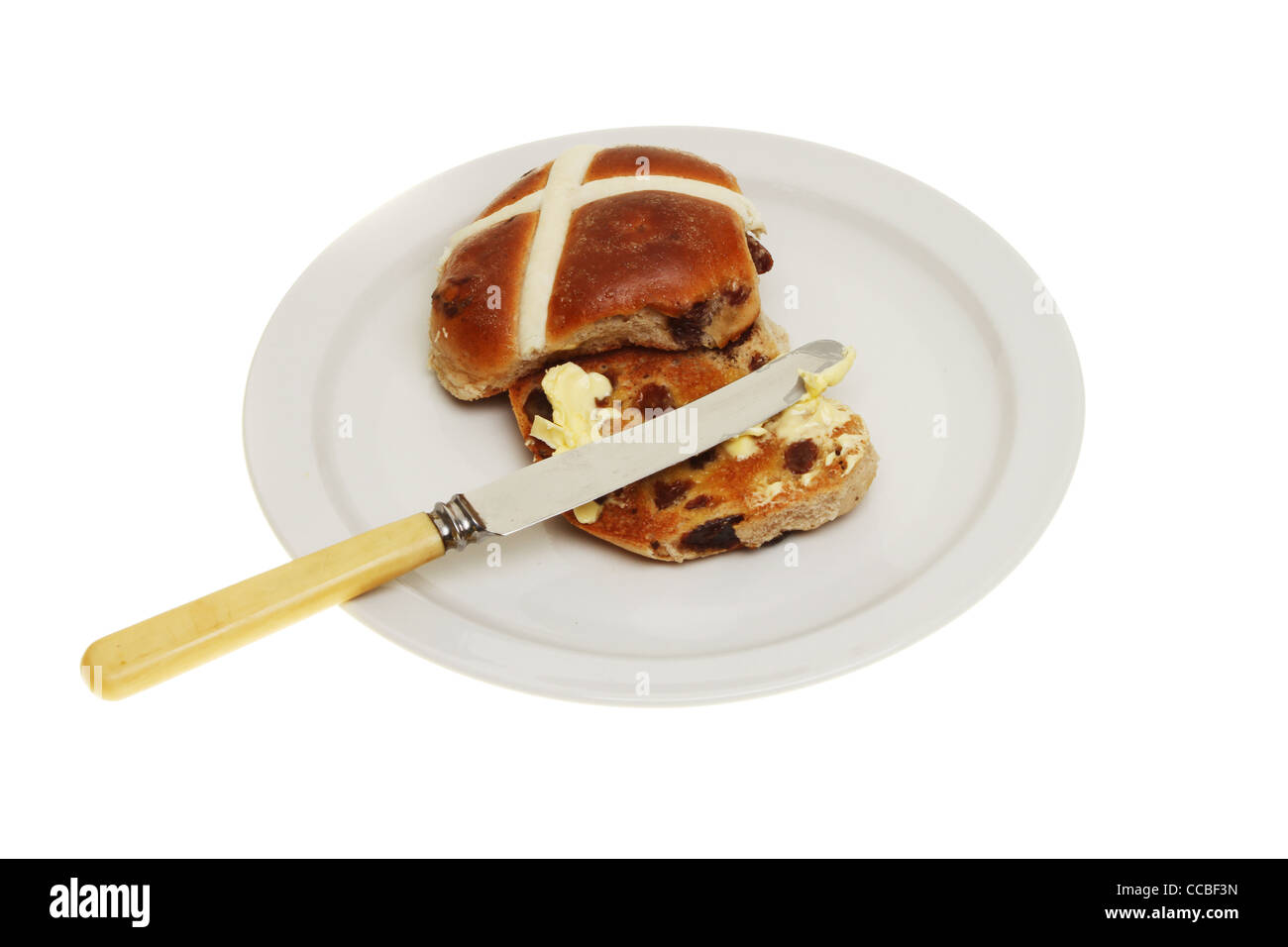 Et grillées chaudes beurrées cross bun avec un couteau sur une plaque isolés contre white Banque D'Images