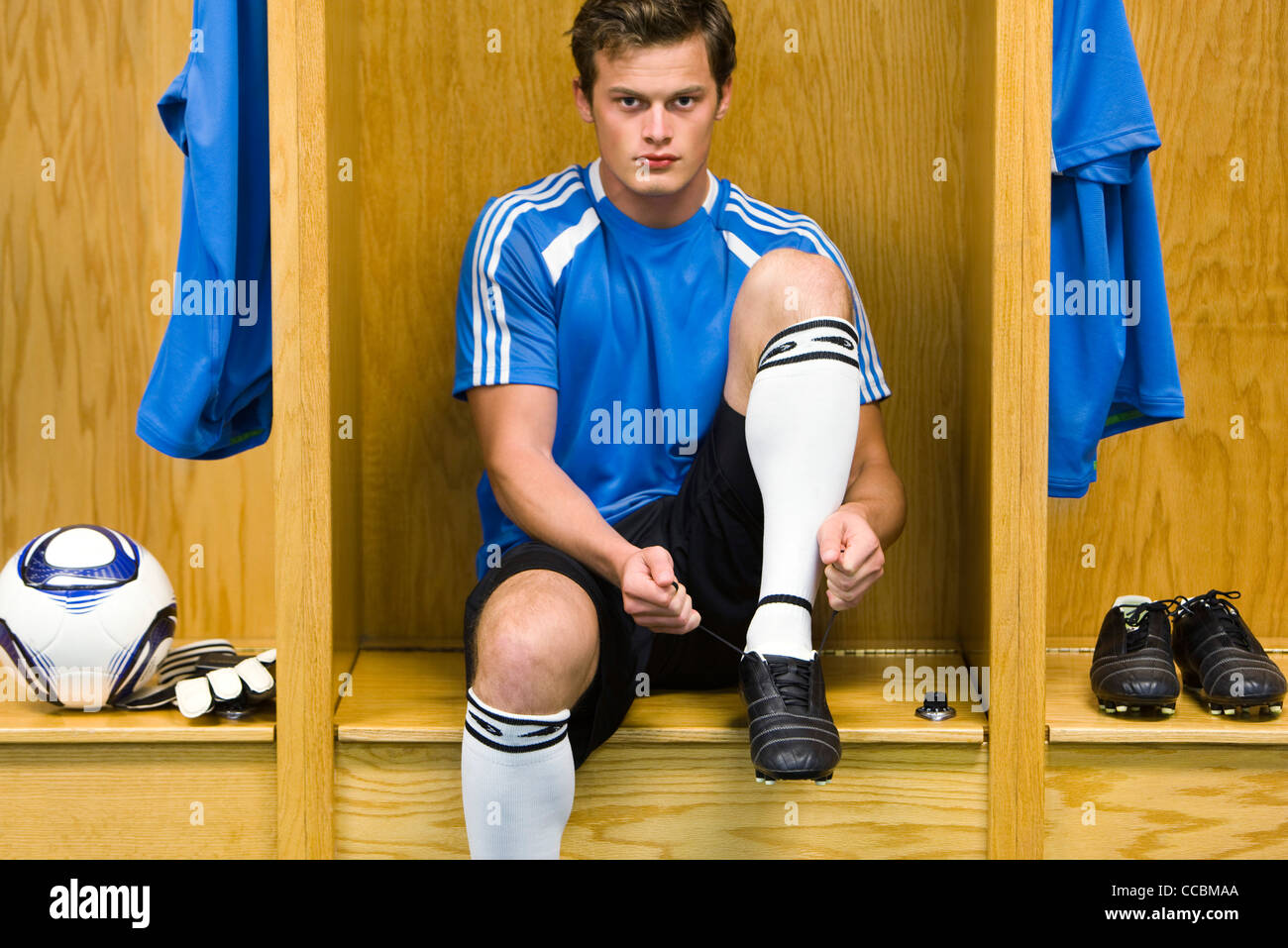 Jeune joueur de soccer chaussures de liage, portrait Banque D'Images