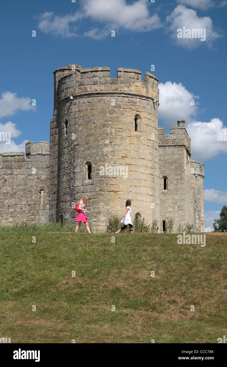 Les visiteurs de marcher sur les douves mur en face de la tour sud-est du 14ème siècle Château de Bodiam, East Sussex, Angleterre, Royaume-Uni. Banque D'Images