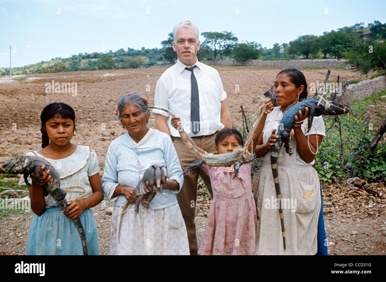 Un touriste européen pose pour une photo souvenir avec les villages mexicains tenant divers reptiles y compris un tatou et Iguana. Banque D'Images