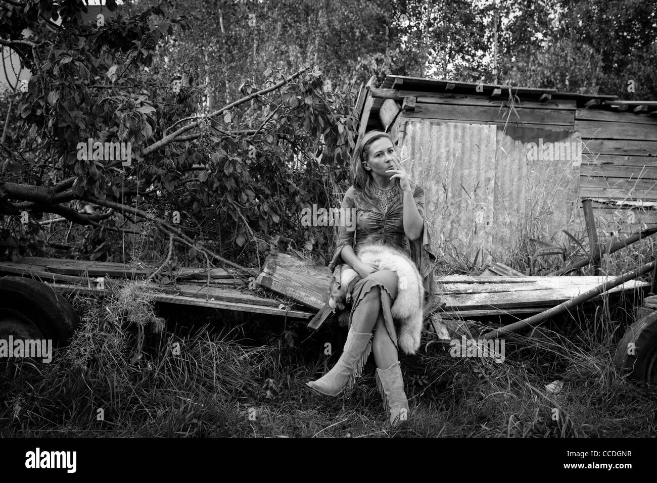 Fille assise sur une remorque en bois et fumer une cigarette. Paysage rural polonais. Banque D'Images