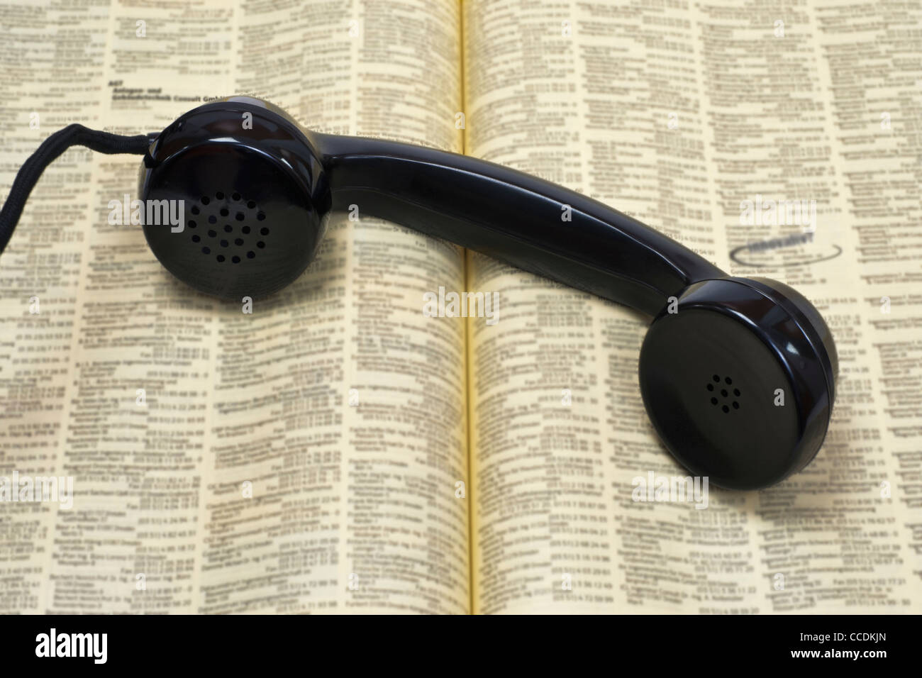 Photo détail d'un vieux téléphone récepteur, couché sur un annuaire téléphonique Banque D'Images