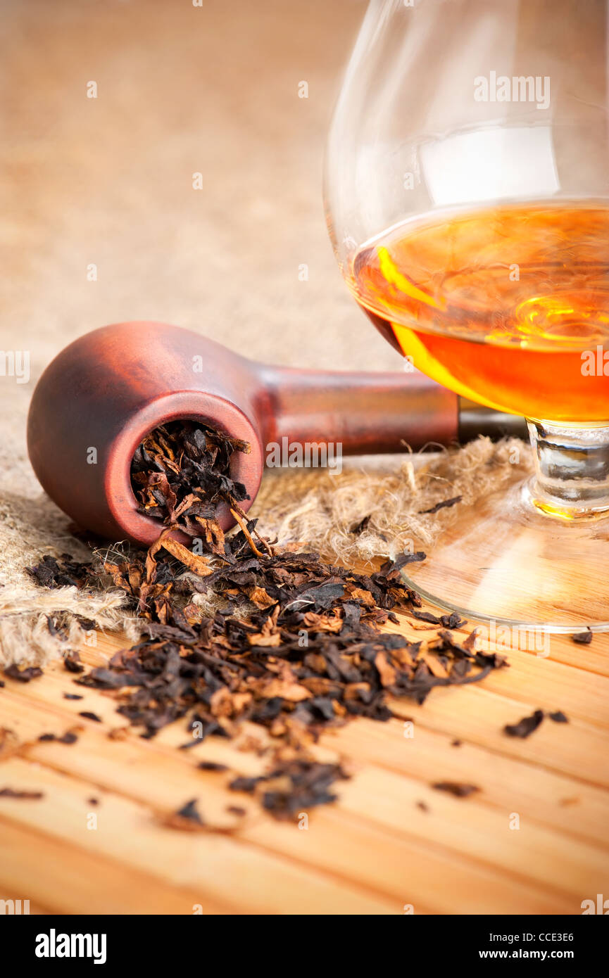 Verre de cognac et le tuyau au tabac sur la table en bois avec de la toile de lin Banque D'Images