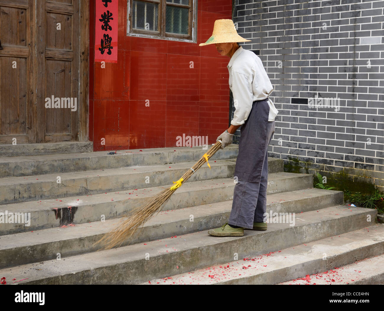 Street Sweeper nettoyage d'artifice rouge papier avec un balai fait maison dans fuli près de Yangshuo chine Banque D'Images