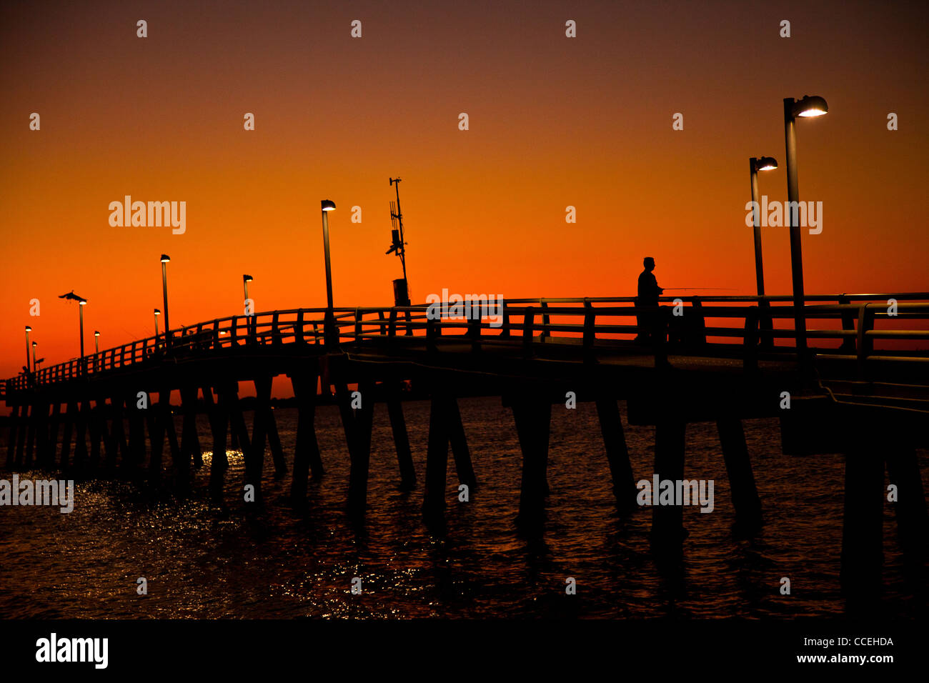 Pêcheur sur un quai en silhouette au coucher du soleil à Sarasota, Floride Banque D'Images