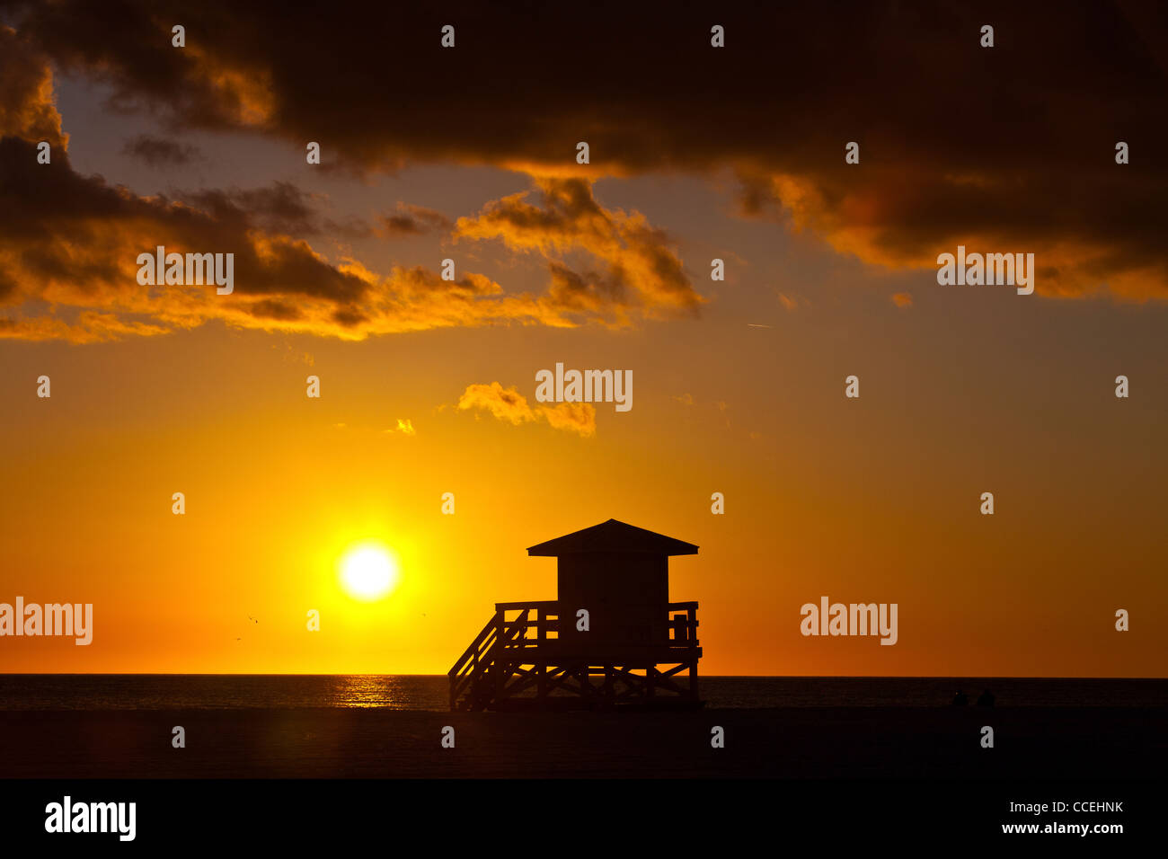 Silhouettes au coucher du soleil sur la station de sauveteur célèbre sable blanc de poudre Siesta Key Beach, Sarasota en Floride Banque D'Images