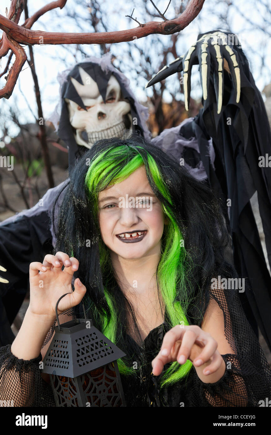 Petite sorcière holding lanterne avec personne en Grim Reaper en arrière-plan permanent Banque D'Images