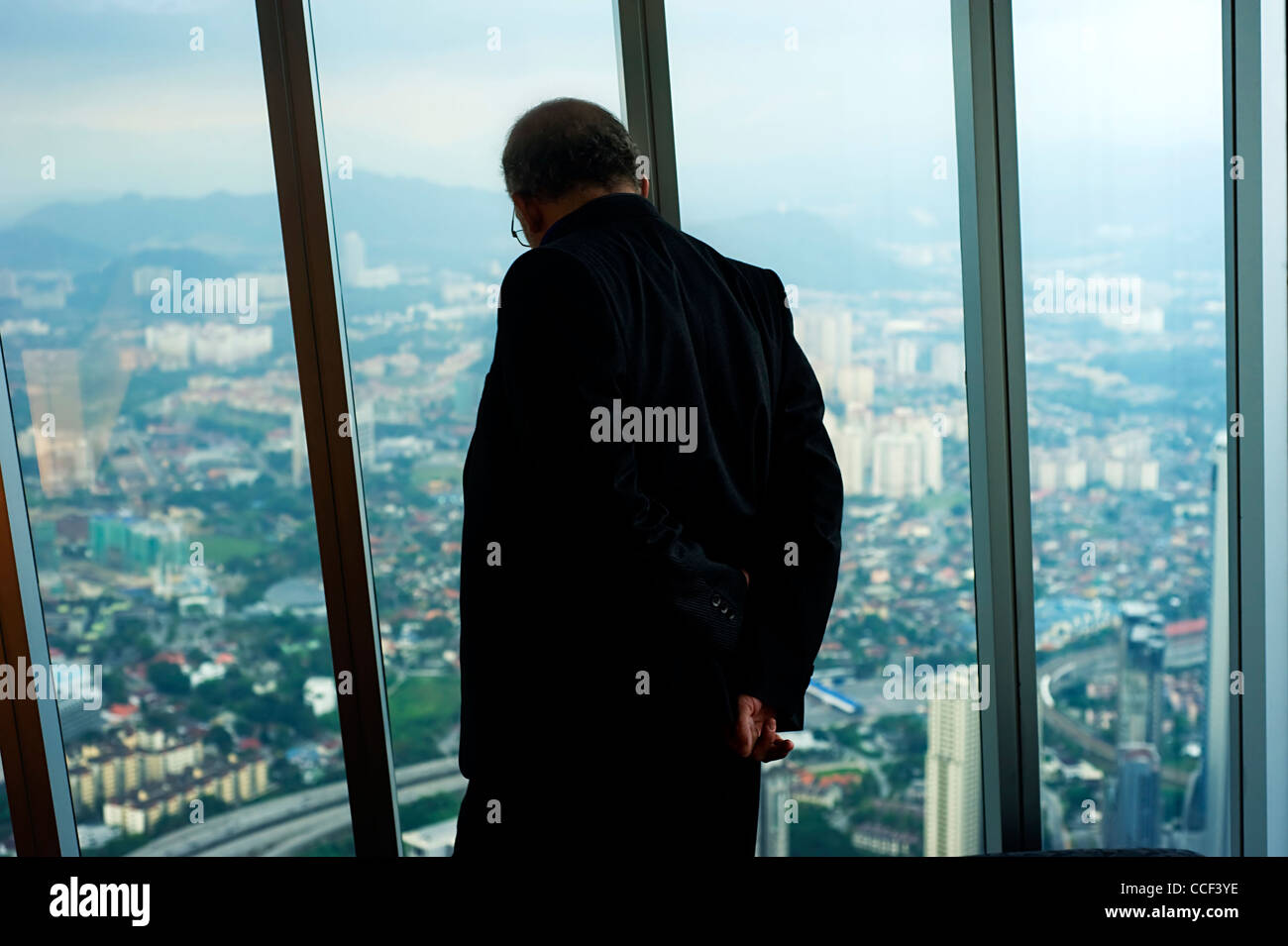 Businessman looking through the window de Petronas Twin Tower jusqu'à la ville de Kuala Lumpur. Banque D'Images