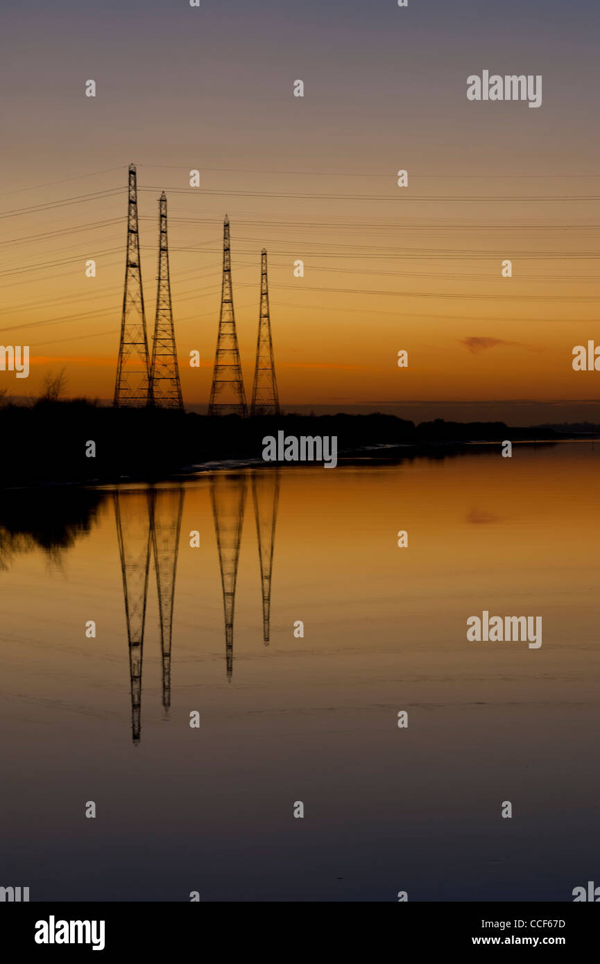 Pylônes enjambant la rivière Ribble au coucher du soleil Banque D'Images