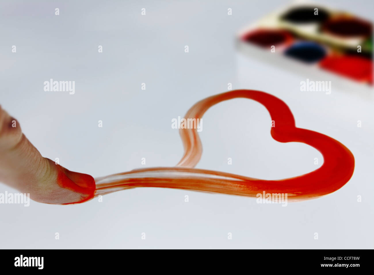 Un cœur rouge dessiné avec le doigt, en arrière-plan une palette de couleurs Banque D'Images
