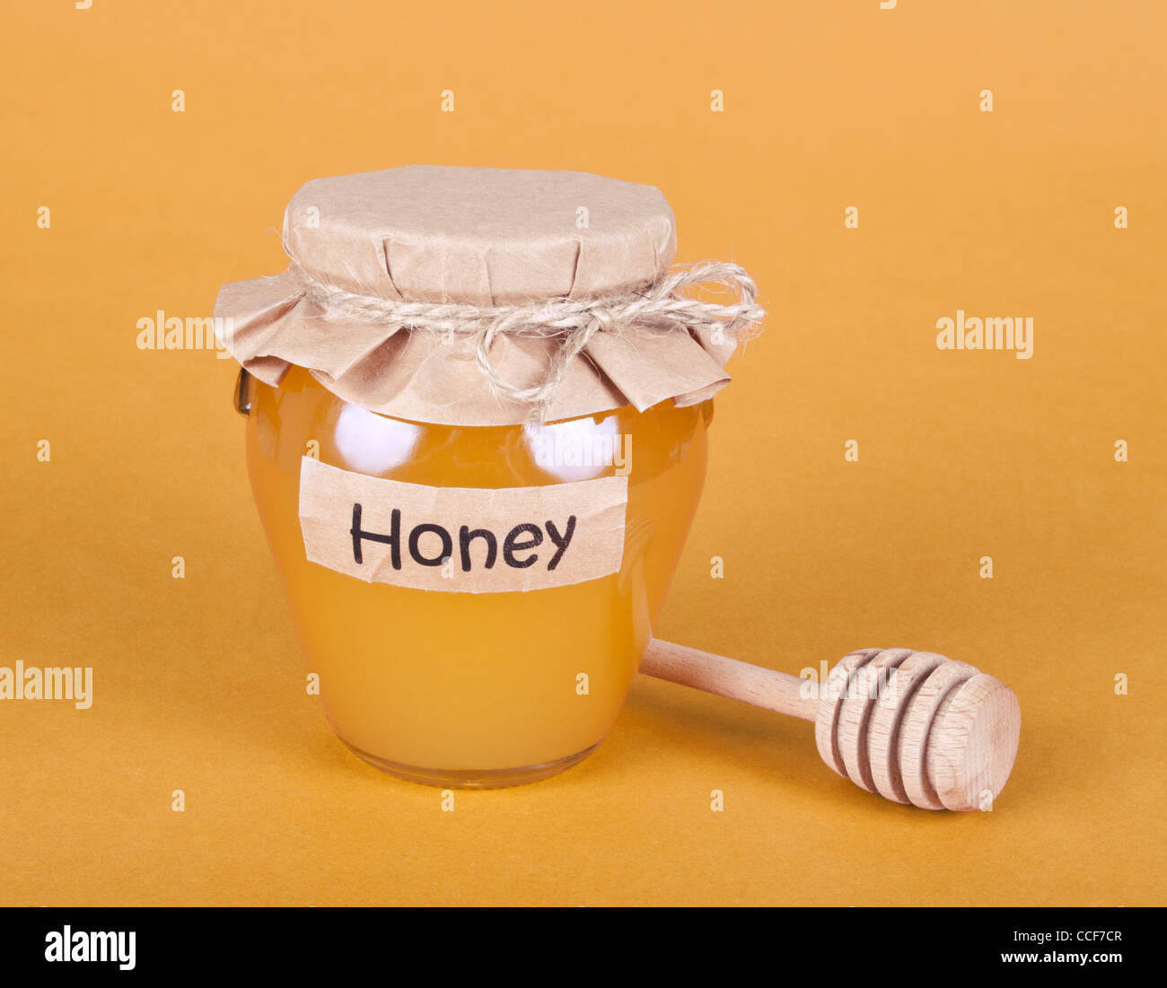 Pot de miel en verre avec un drizzler sur fond jaune Banque D'Images