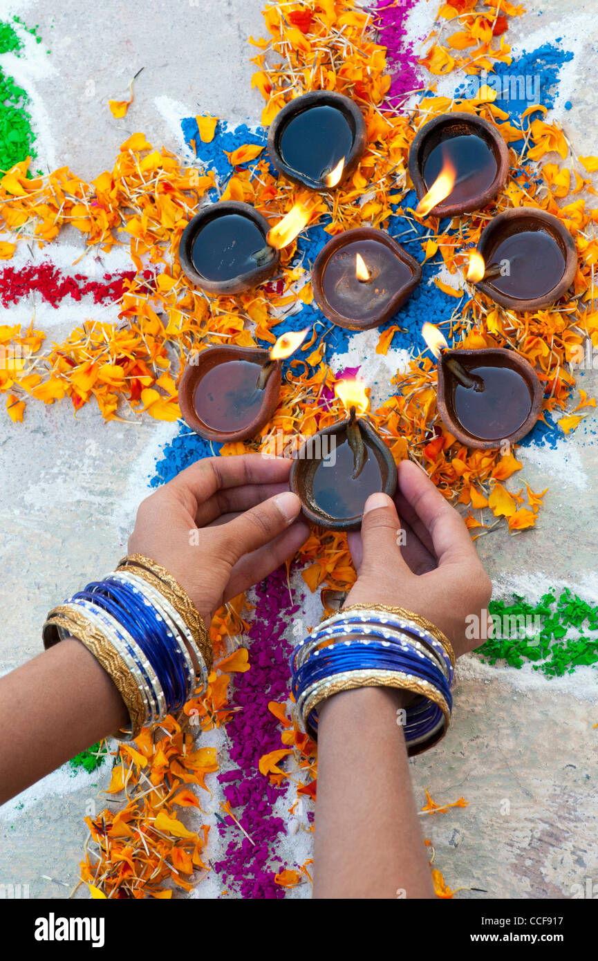 L'Inde girl ajout de lampes à huile à un festival Rangoli design. Puttaparthi, Andhra Pradesh, Inde Banque D'Images