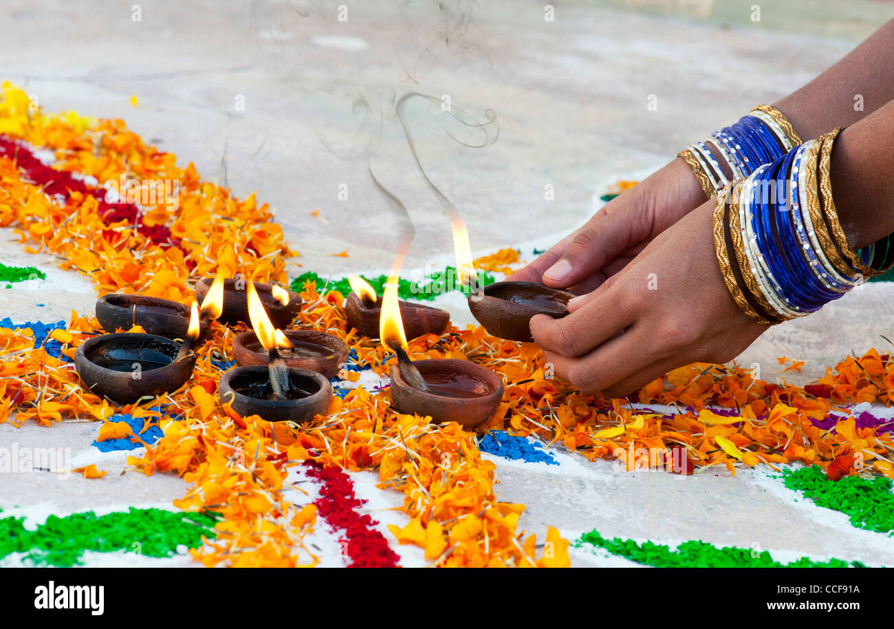 L'Inde girl ajout de lampes à huile à un festival Rangoli design. Puttaparthi, Andhra Pradesh, Inde Banque D'Images