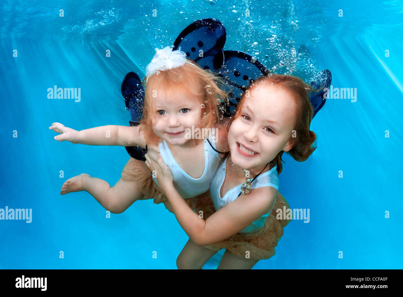 Deux jeunes filles avec des ailes de papillon de sourire et s'amuser sous l'eau Banque D'Images