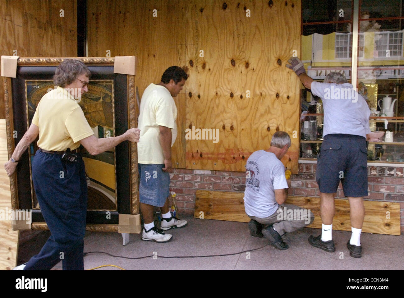 090104 atteint --Lake Worth ---Evelyn Dublin, cq, la gauche porte une peinture sur son chemin dans la galerie d'antiquaires d'hier à 716 LakeAvenue comme Juan Morales, Steve Gaffney, CQ, et Carmin Yannotta,QC, à mettre des planches sur la fenêtre. Dublin, d'Dublin-Kahn Art Gallery a un stand mis en place dans le magasin où elle vend des p Banque D'Images