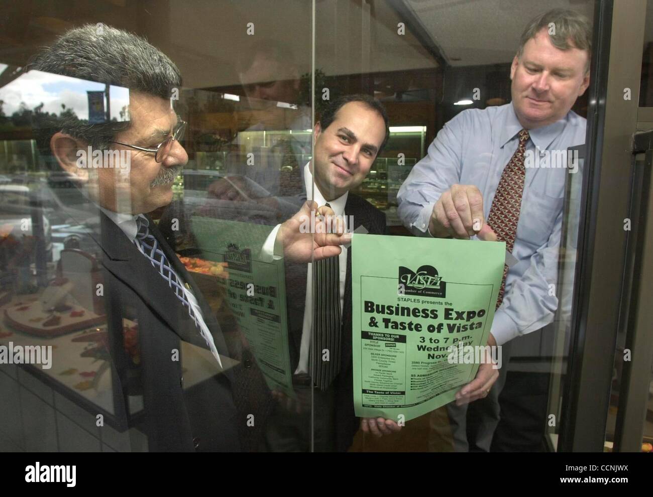 (Publié le 07/11/2004, N-5) Affichage d'un signe la promotion de la Chambre de Commerce du Vista Business Expo & Dégustation de Vista dans la fenêtre avant de Vista de bijoux de qualité au centre-ville de Vista sont, LtoR : MICHAEL CAVATAIO, de Californie Banque Communautaire, JOHN SHAKARIAN (du magasin de bijoux), et JIM BAUMANN, Presiden Banque D'Images