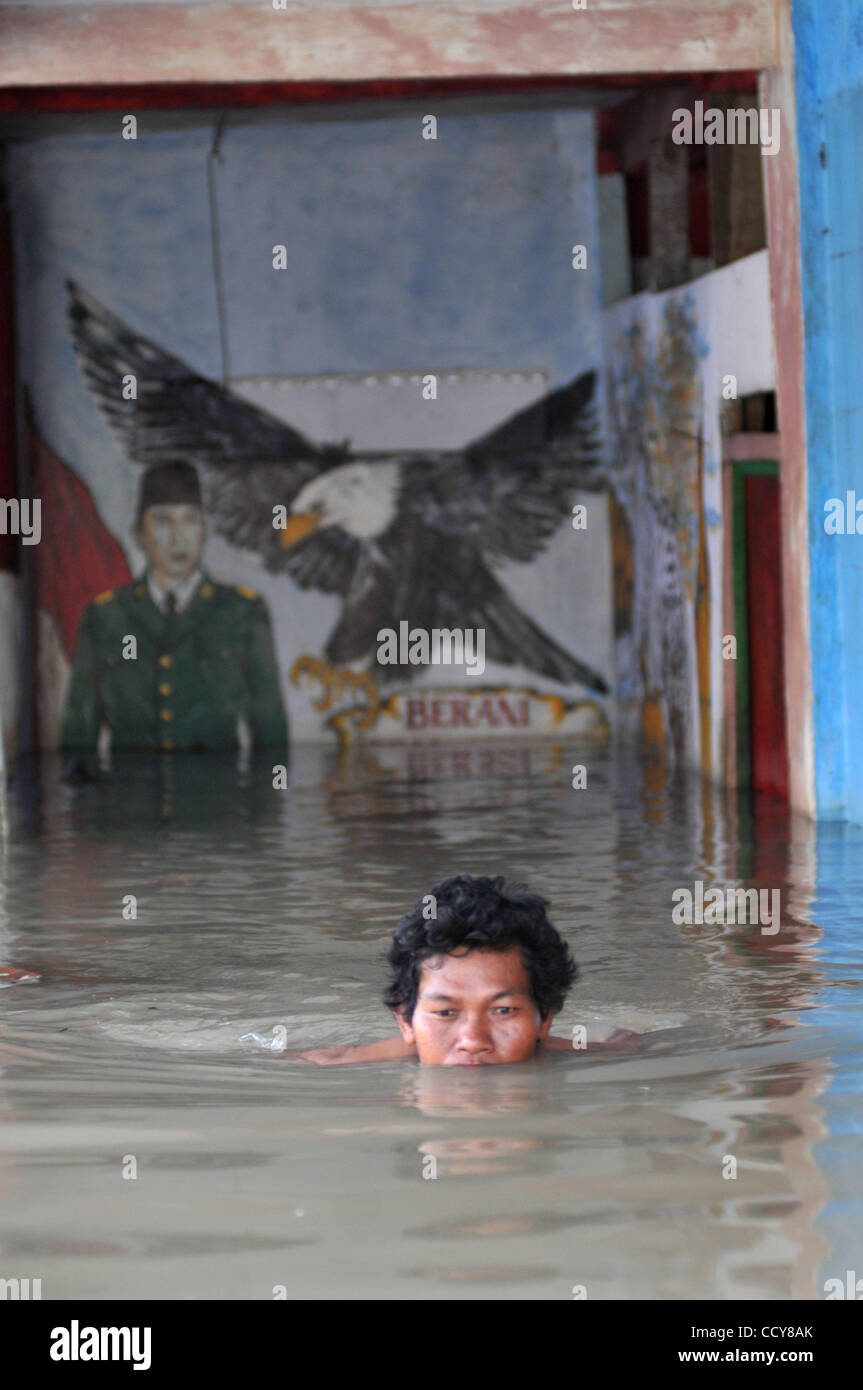 Nager à travers les résidents des eaux d'inondation dans la région de Karawang, province de Java Ouest, l'Indonésie. Le 23 mars 2010. Huit des milliers de maisons dans la région ont été inondées par l'eau en raison des fortes pluies et le débordement du fleuve Citarum. 32 000 personnes comme refuges. Banque D'Images