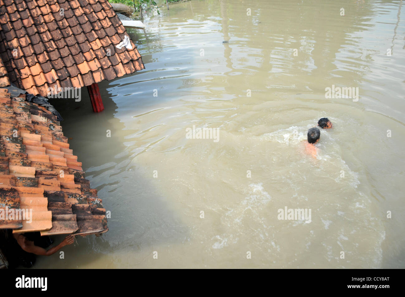 Nager à travers les résidents des eaux d'inondation dans la région de Karawang, province de Java Ouest, l'Indonésie. Le 23 mars 2010. Huit des milliers de maisons dans la région ont été inondées par l'eau en raison des fortes pluies et le débordement du fleuve Citarum. 32 000 personnes comme refuges. Banque D'Images